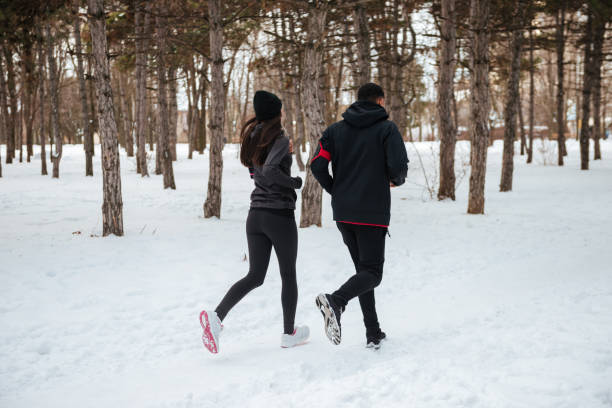 istock Back view of young couple jogging in forest together 1348099297