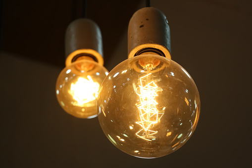 Two vintage incandescent Edison type bulbs shine on a dark background. Loft style decoration