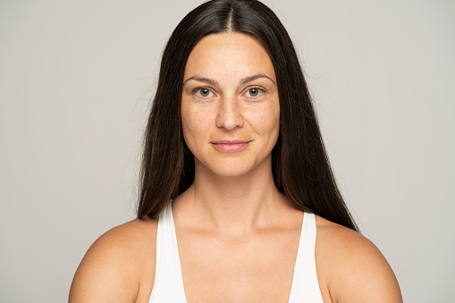 a young smiling woman without makeup with long hair on a gray background