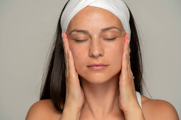 a young woman with closed eyes massaging her face - 臉部按摩 個照片及圖片檔