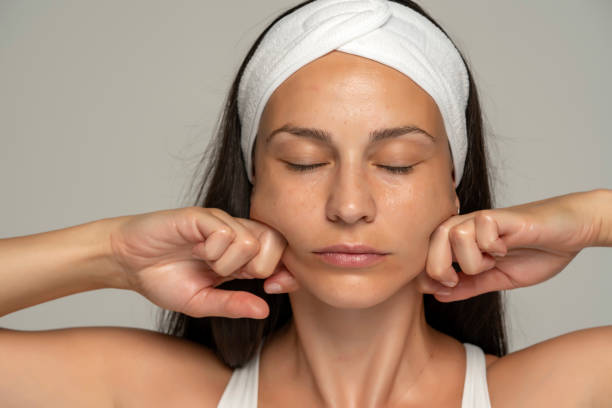 顔をマッサージする若い女性 - facial massage ストックフォトと画像