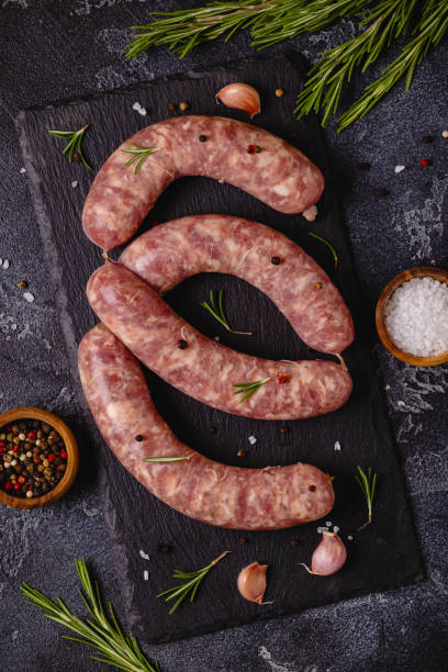 istock Raw sausages and ingredients for cooking on a black stone table 1348105817