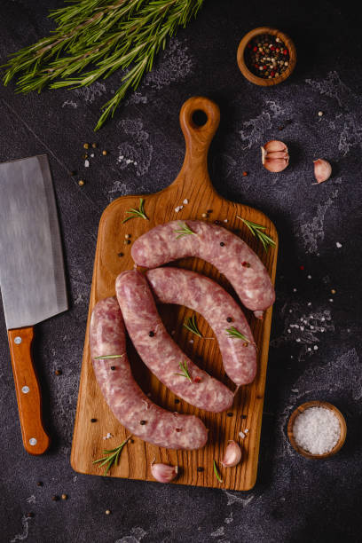 istock Raw sausages and ingredients for cooking on a black stone table 1348105888