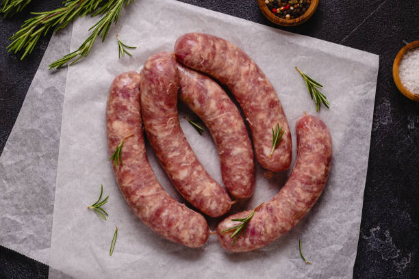 istock Raw sausages and ingredients for cooking on a black stone table 1348105940
