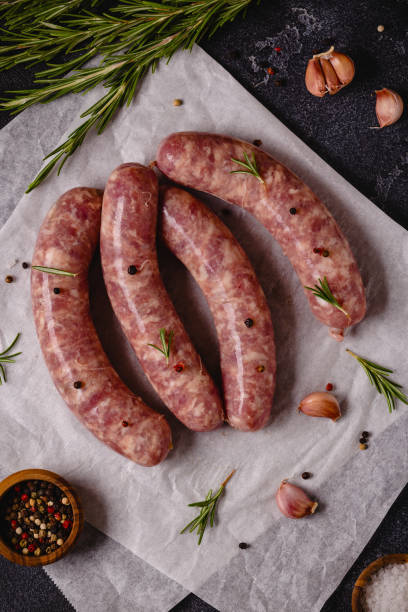 istock Raw sausages and ingredients for cooking on a black stone table 1348106110