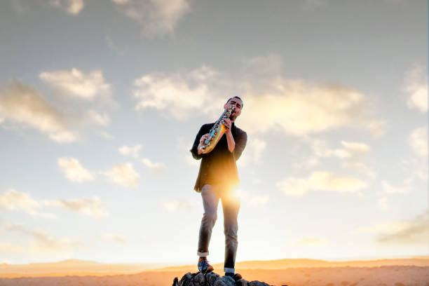 latin musician playing saxophone in the desert between clouds