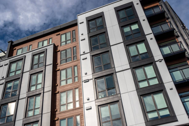 low angle view of a modern style business building, with lots of windows on a sunny, cloudy day - apartamento imagens e fotografias de stock