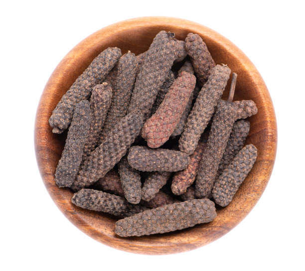 Long pepper in wooden bowl, isolated on white background. Heap of pippali or piper longum. Top view. Long pepper in wooden bowl, isolated on white background. Heap of pippali or piper longum. Top view capsicum annuum longum stock pictures, royalty-free photos & images