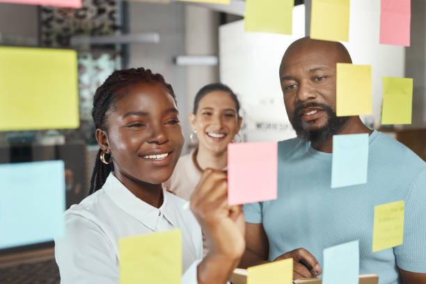 Shot of a group of businesspeople brainstorming with sticky notes on a glass screen Planning is indispensable transparent wipe board stock pictures, royalty-free photos & images