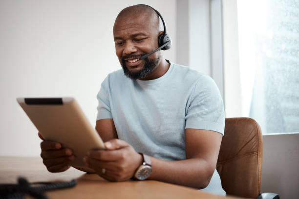 istock Shot of a man using a digital tablet while working in a call center 1348113226