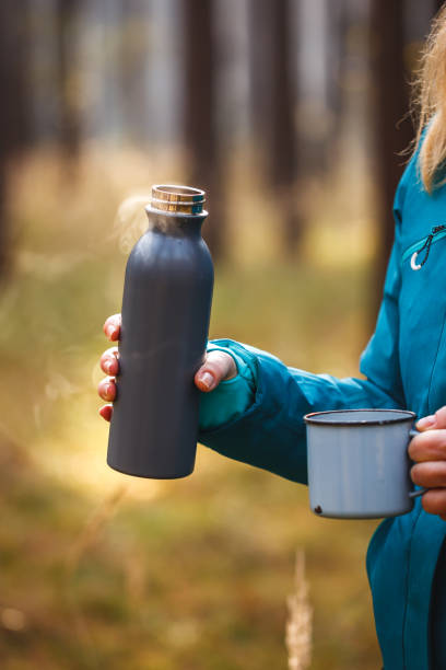 istock Hiker holding thermos with hot coffee in forest 1348113608