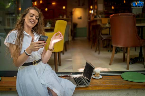 istock Businesswoman using laptop while enjoying work at cafe table with cup of coffee 1348114566