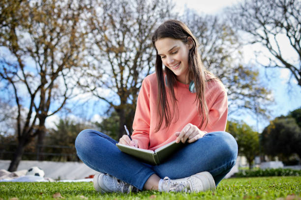 istock Shot of a student writing in her notebook while sitting outside 1348115459
