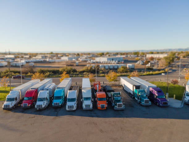 sattelschlepper, die nebeneinander auf einem autohof für eine pause auf halbem weg der elfstündigen begrenzten fahrzeit zum ausruhen geparkt sind - delivering freedom shipping truck stock-fotos und bilder