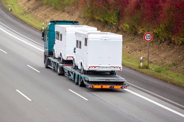 a flatbed truck featuring two vans on its back