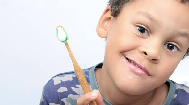 istock boy brushing teeth with a tooth brush stock photo 1348118413