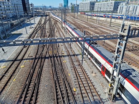 Zurich  with a larg track field from the federal rail sevice company SBB. The wide angle image shows the large trackfield with a train approaching on Zurich Mainstation. The image was captured during summer season.