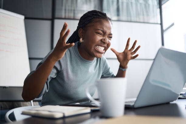 オフィスでラップトップを使用している間に怒って見ている若いビジネスウーマンのショット - adult anger furious irritation ストックフォトと画像