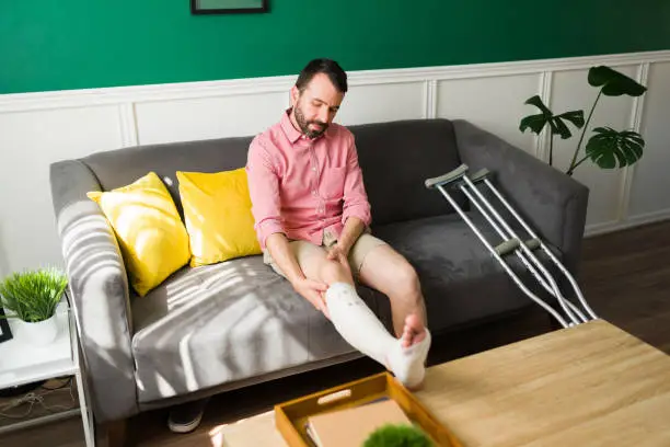 Photo of Ill man with a bandaged foot relaxing