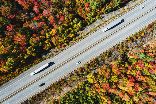 Semi trucks on a highway surrounded by Autumn colours.