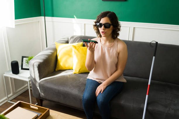 Disabled woman using her phone Attractive blind woman talking on the phone with the loudspeaker on. Caucasian woman with a disability using the voice assistant in her smartphone blind persons cane stock pictures, royalty-free photos & images