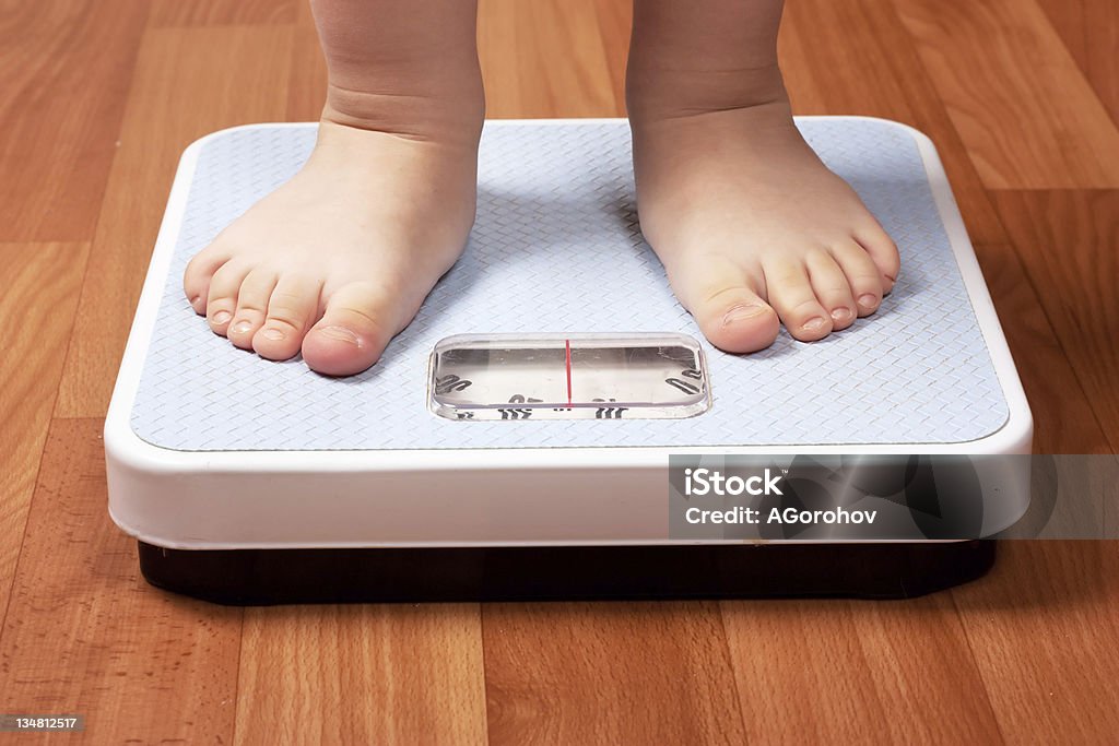 Scales Closeup view of scales on a floor and kids feet Child Stock Photo