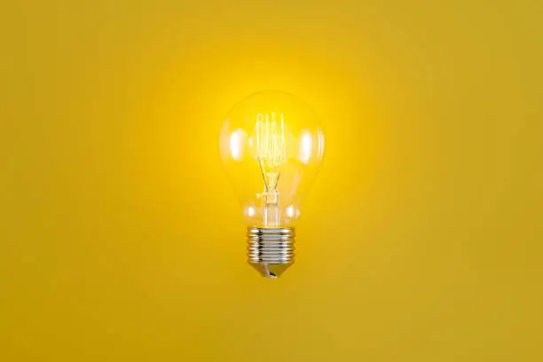 Photo of glowing classic light bulb with filament