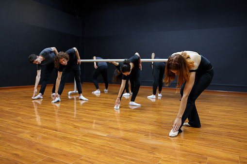 Teacher guiding a group of dancers doing stretching exercises in a dance class