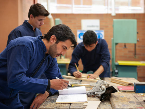 istock Student building furniture with wood in a carpentry class with a group 1348130148