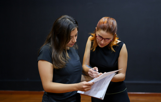 Latin American drama teacher helping a student with her script in an acting class - performing arts concepts