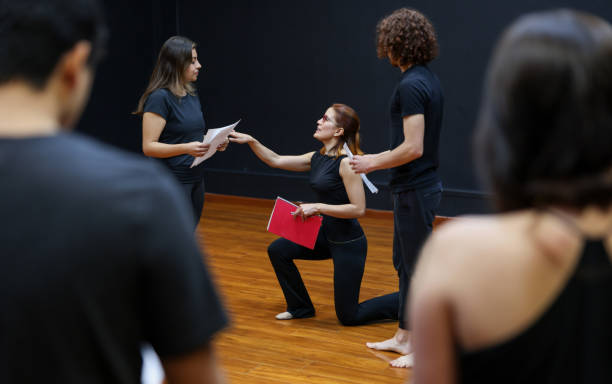 entrenadora de actuación dirigiendo un ejercicio de improvisación con sus alumnos en una clase de teatro - actuar fotografías e imágenes de stock