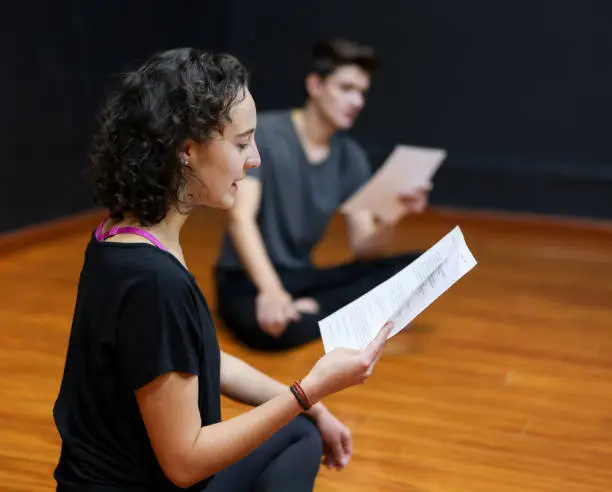 Group of drama students reading a script in a theatre class - performing arts concepts