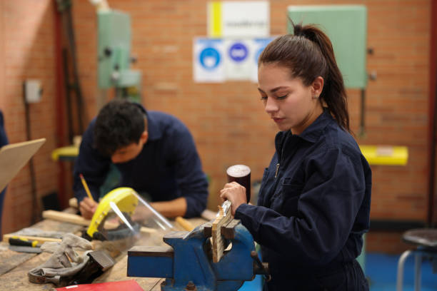 Female student planning wood with a hand plane at the university