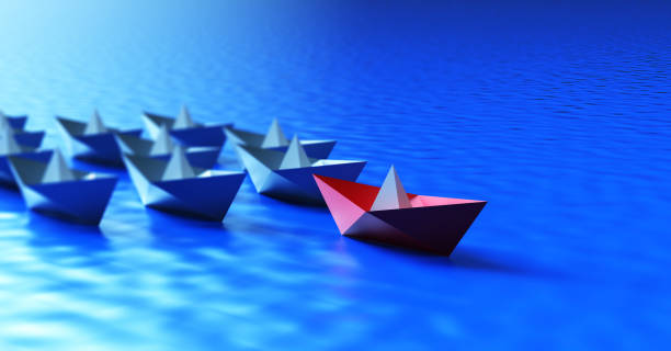 istock Leadership concept with red paper ship leading among white 1348130887