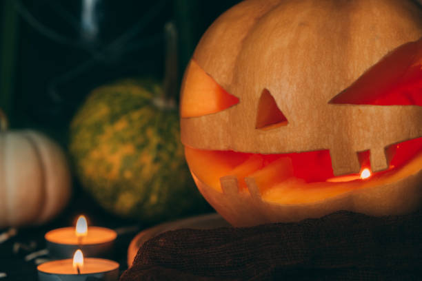 istock Halloween pumpkin carved on a board close-up, a candle is burning inside. 1348131018