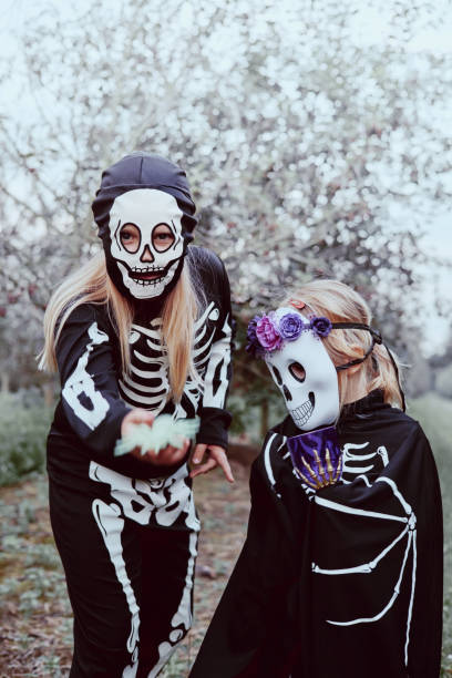 istock Two sisters dressed up as skeleton and witch having fun at Halloween party and trick-or-treating outdoors 1348137474