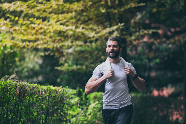 istock Determined young man running outside in the park. Fit boy doing exercise outdoor. Beautiful sporty male run alone. Sweaty athlete training with towel. Wellness, health, sport, fitness open air concept 1348138103