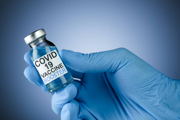Hand in blue medical gloves holding a vaccine vial with Covid 19 Vaccine Booster text, for Coronavirus booster shot. Hand in blue medical gloves holding a vaccine vial with Covid 19 Vaccine Booster text, for Coronavirus booster shot. booster dose photos stock pictures, royalty-free photos & images