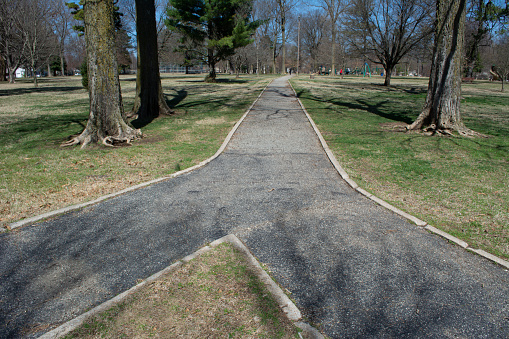 Two paths converge together or there is a fork in the path leading to different directions. A paved path leads through Phelps Grove Park in Springfield, Missouri.