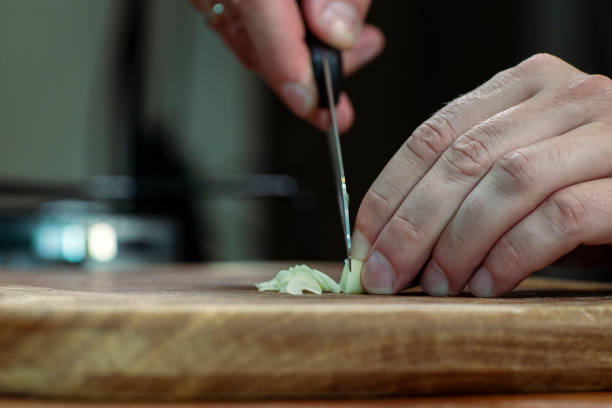 istock Chopping garlic on a wooden board for cooking. 1348144031