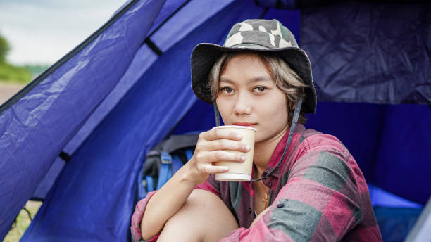 istock young Asian female drink coffee in tent camping 1348146272