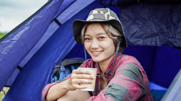 istock young Asian female drink coffee in tent camping 1348146299