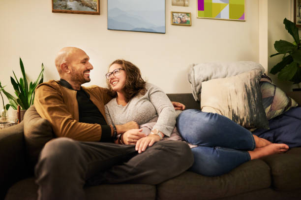 istock Smiling couple looking at each other while relaxing together at home 1348150517