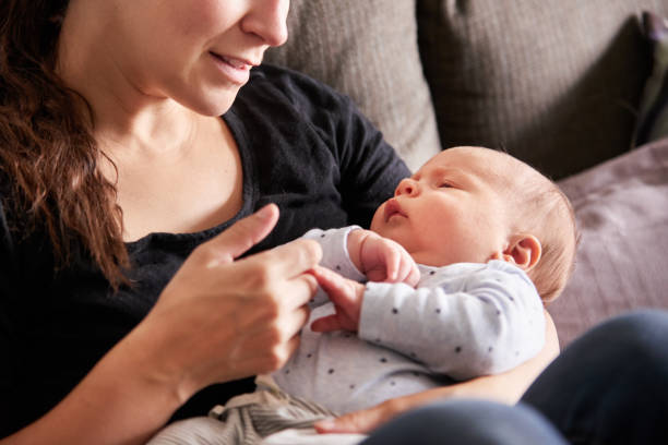 istock Loving mother sitting at home and holding her sleeping baby's hand 1348151376