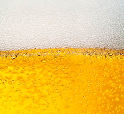 Glass of wheat beer with foam on dark background