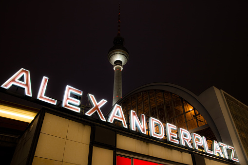 Berlin Alexanderplatz sign, TV tower and train station by night.