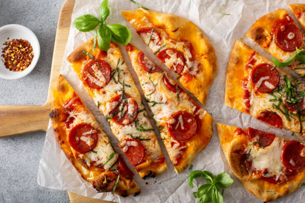 Flatbread pepperoni pizza with basil Flatbread pepperoni pizza topped with fresh basil sliced, top view flatbread stock pictures, royalty-free photos & images