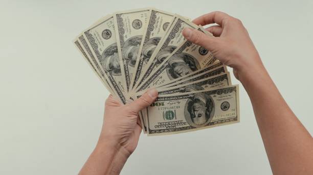 istock women's hands count dollar bills spreading out a fan in front of them 1348168163
