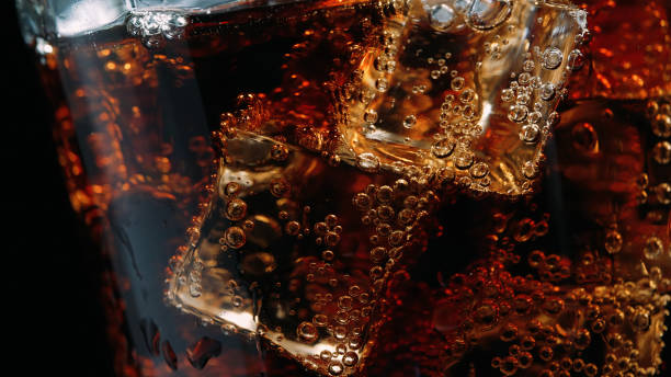 primer plano de un vaso de cola con cubitos de hielo y burbujas - cola gaseosa fotografías e imágenes de stock