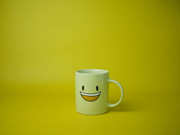 istock yellow coffee mug with smile emoticon icon 1348174887